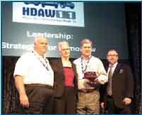 Don Purcell (left) and Keith McLemore, co-owners of Stone Truck Parts, accept the Truck Parts & Service Distributor of the Year award from Truck Parts & Service Executive Editor Denise L. Rondini. Craig Kruckeberg, CEO, Minimizer and the program’s sponsor, was also on hand.