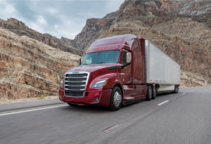 freightliner truck on the highway with red cab and white trailer