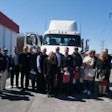 The group of dealer principals and Daimler executives from Australia and Peach State President Rick Reynolds pose in front of a New Cascadia following the Forest Park facility tour.