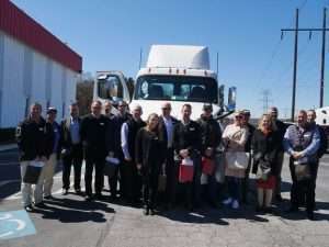 The group of dealer principals and Daimler executives from Australia and Peach State President Rick Reynolds pose in front of a New Cascadia following the Forest Park facility tour.