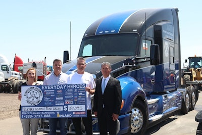 People posing with 'Everyday Heroes' Kenworth T680 truck at auction