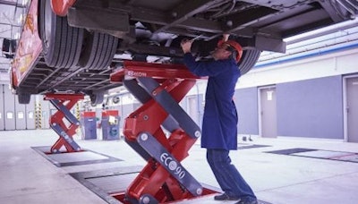 Technician Standing Under Truck On A Lift