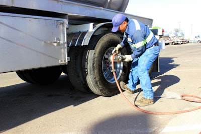 man putting air into a trailer's tire