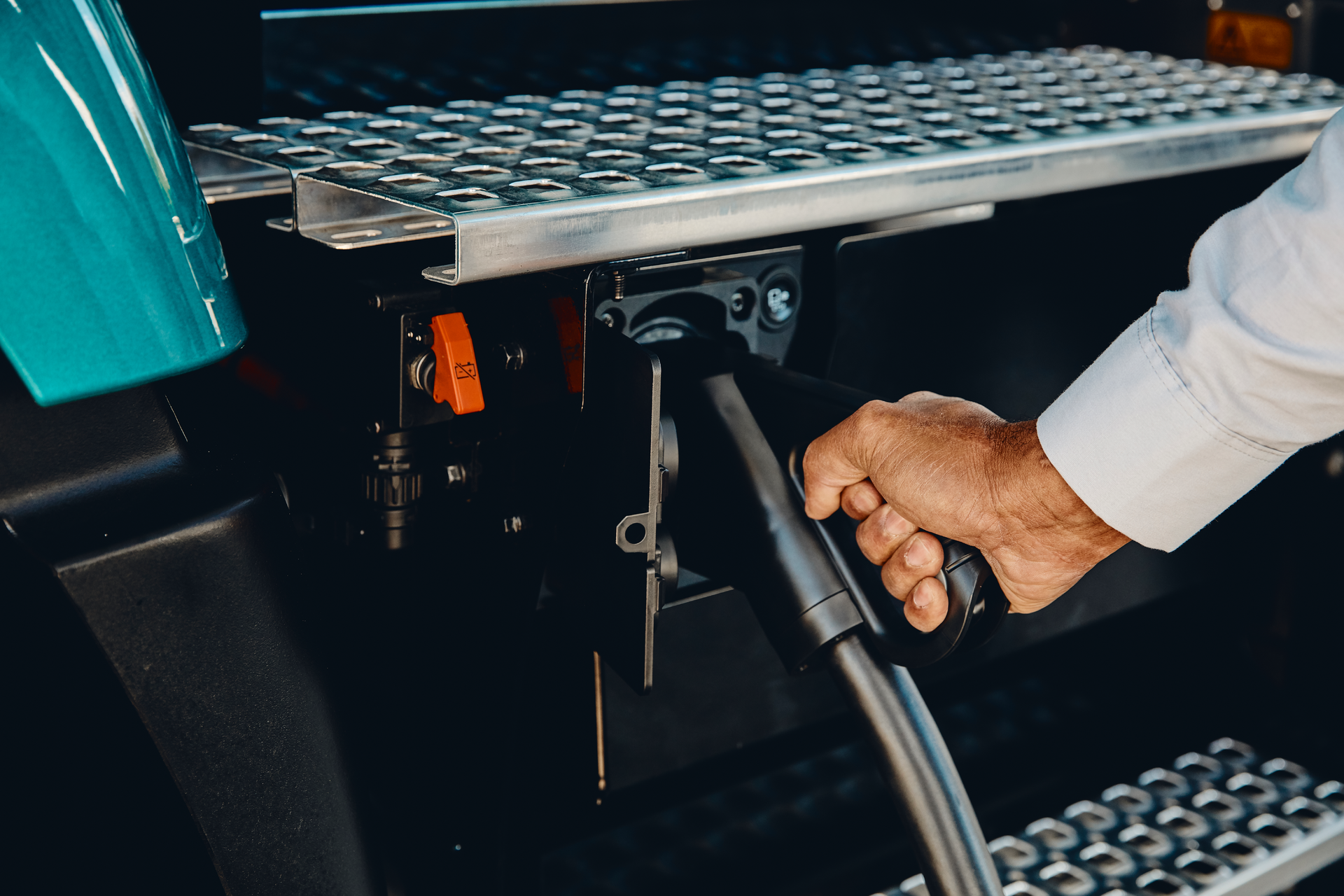 A person inserting an electric charging cable into a charging port on a Volvo VNR