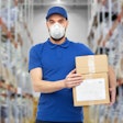 Masked employee holding boxes
