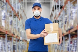 Masked employee holding boxes