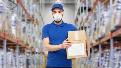 Masked employee holding boxes