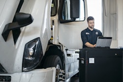 Volvo Technician working on a tablet beside a semi-truck