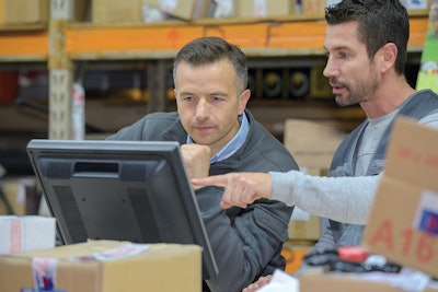 Two men looking at information on a computer monitor