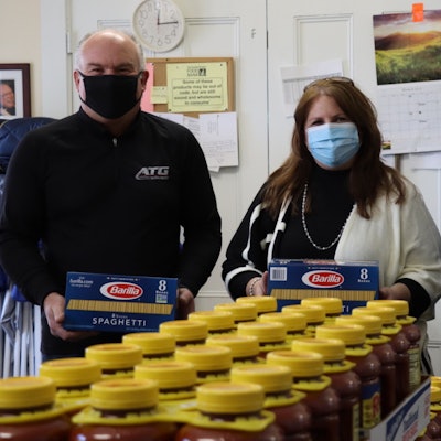 Advantage Truck Group President and CEO Kevin Holmes with Paula Hardy, volunteer at the Raynham Food Basket, delivering 100 boxes of pasta and 100 jars of sauce to the food pantry in Raynham, Mass., where ATG will be opening a new dealership this summer.