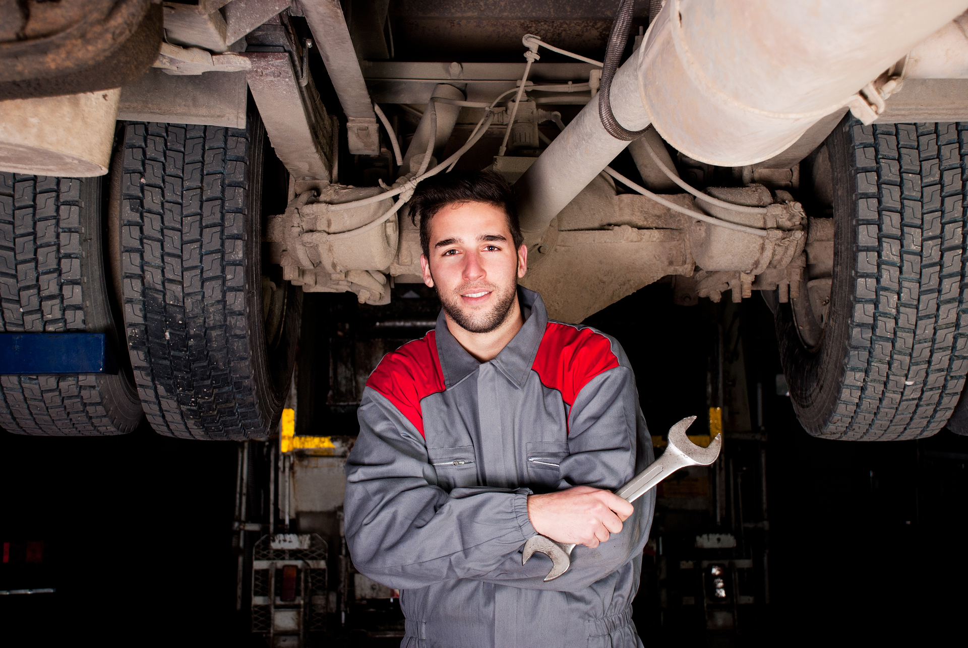 Younger technician poses under truck