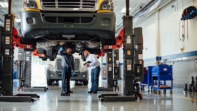 Technicians diagnosing an undercarriage issue