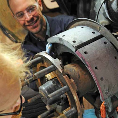Technicians inspecting a brake drum and wheel end