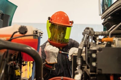 A trained technician wearing personal protective equipment removes the junction box on a Volvo VNR Electric truck to verify there is no voltage in the traction voltage system.