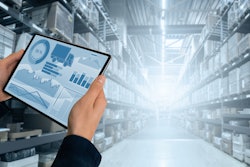 hands holding a tablet with graphs in the of a warehouse