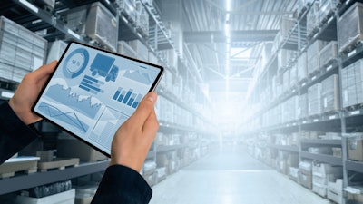 hands holding a tablet with graphs in the of a warehouse