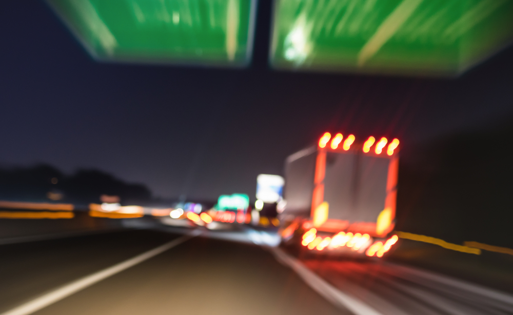 Blurred image of trucks driving on expressway at night.
