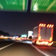 Blurred image of trucks driving on expressway at night.