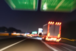 Blurred image of trucks driving on expressway at night.