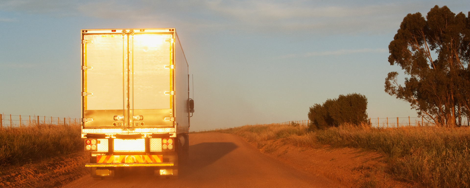 Tractor trailer driving down a rural road.