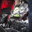 Truck technician holding wrench in front of a truck.