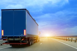 Truck on the road driving into rising sun.