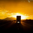 Truck driving toward sun on highway