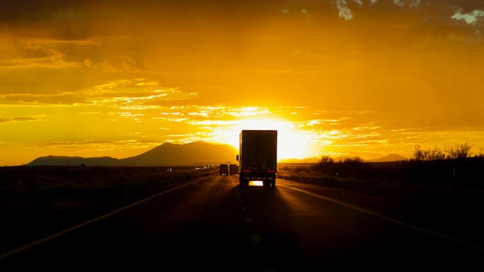 Truck driving toward sun on highway