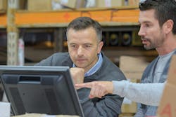 Employees looking at computer monitor in warehouse