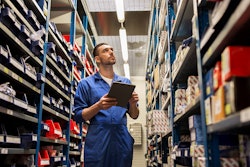 Employee taking parts inventory in warehouse.