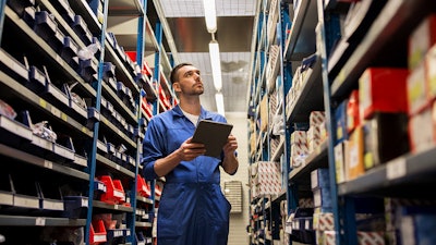 Employee taking parts inventory in warehouse.