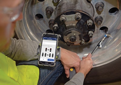Technician using the Goodyear TireOptix App next to a semi-truck's tire