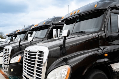 A row of black Freightliner tractors parked