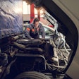 Heavy-duty technician looking underneath Class 8 truck