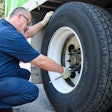 Transervice technician checking tire air pressure on a semi-truck