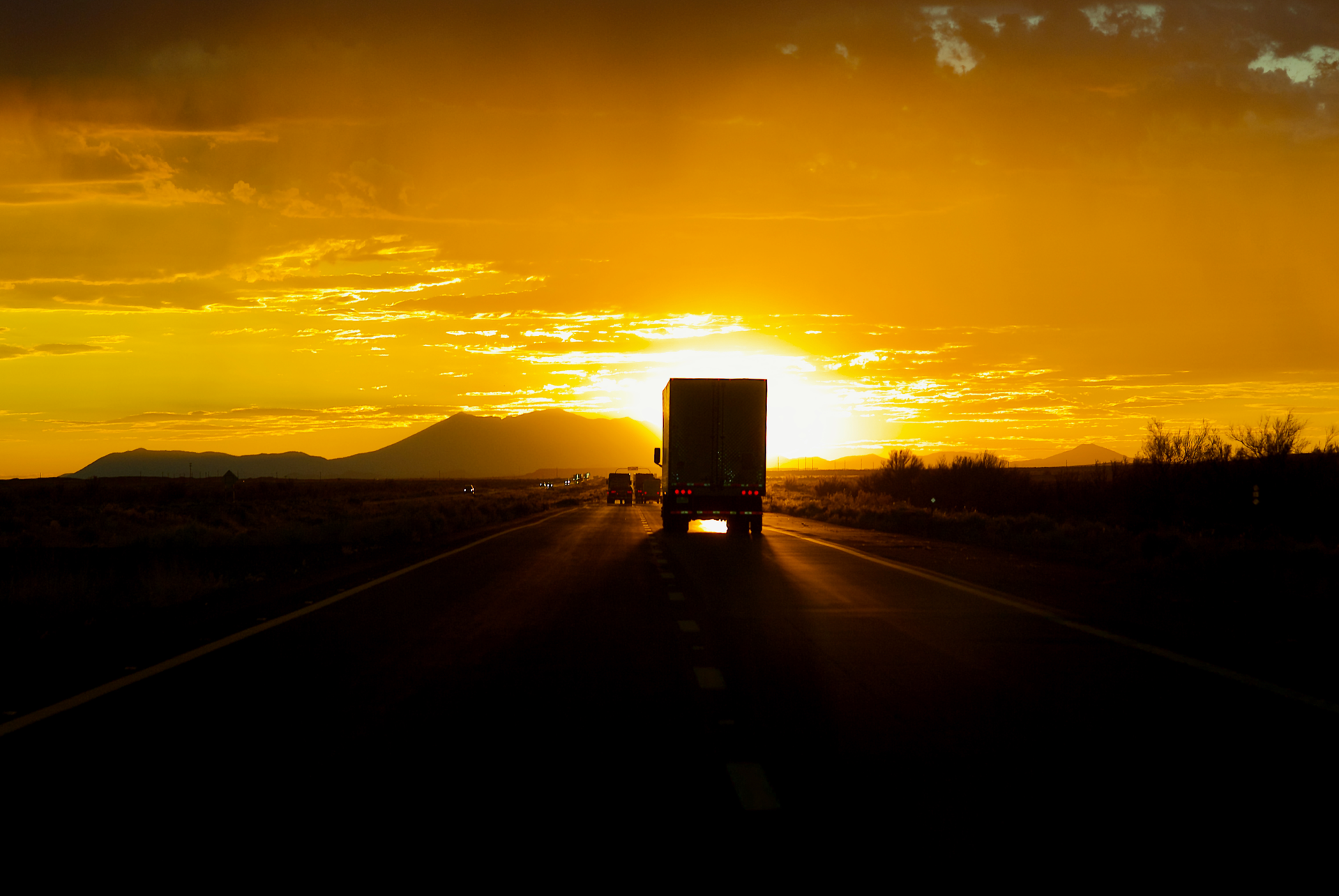 Truck on highway driving toward setting sun