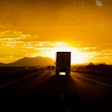 Truck on highway driving toward setting sun