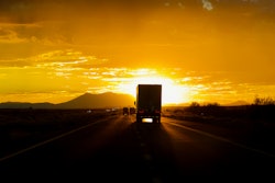 Truck on highway driving toward setting sun