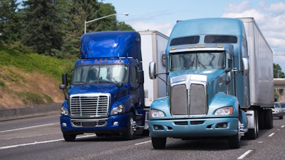 Two blue trucks on the highway