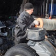 Technician replacing filter on heavy-duty truck.