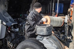 Technician replacing filter on heavy-duty truck.
