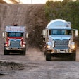 Two Mack Trucks driving down hill on gravel