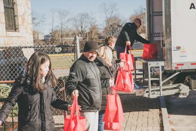 Line of people loading truck with bags of food for Haulin' 4 Hunger organization.