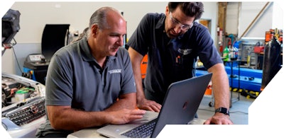 Dorman instructing training a truck technician on a laptop.