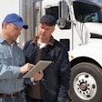 Men using tablet in front of truck