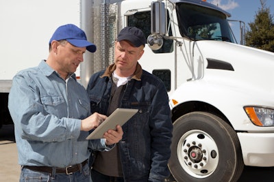 Men using tablet in front of truck