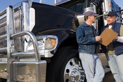 Two men talking next to a truck