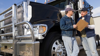 Two men talking next to a truck