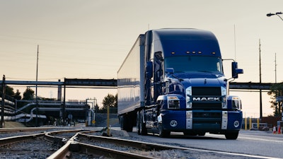 Mack Anthem blue exterior on roadway by rails