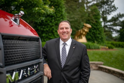 Jonathan Randall stands next to a red Mack truck.